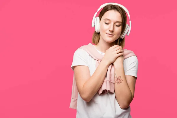 Alegre joven en auriculares escuchando música aislada en rosa - foto de stock