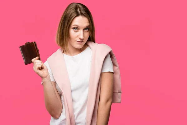 Young woman holding wallet and looking at camera isolated on pink — Stock Photo