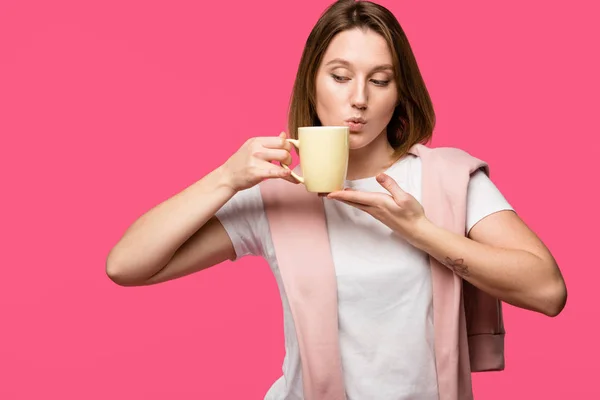 Schöne junge Frau hält Tasse isoliert auf rosa — Stockfoto
