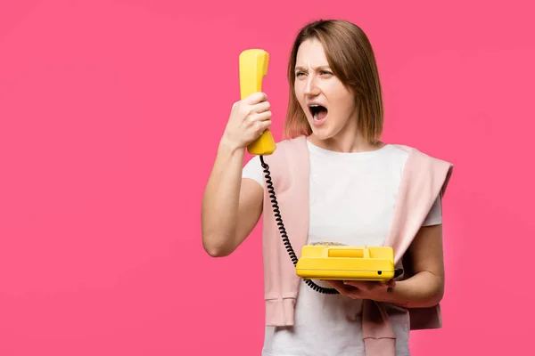 Mujer joven enojada gritando al teléfono aislado en rosa - foto de stock
