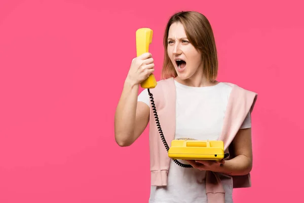 Raiva jovem mulher gritando com auscultador isolado em rosa — Fotografia de Stock