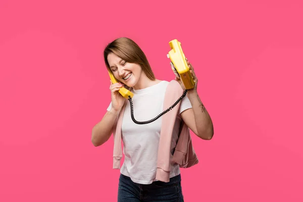 Allegra giovane donna che parla per telefono rotatorio e ride isolata sul rosa — Foto stock