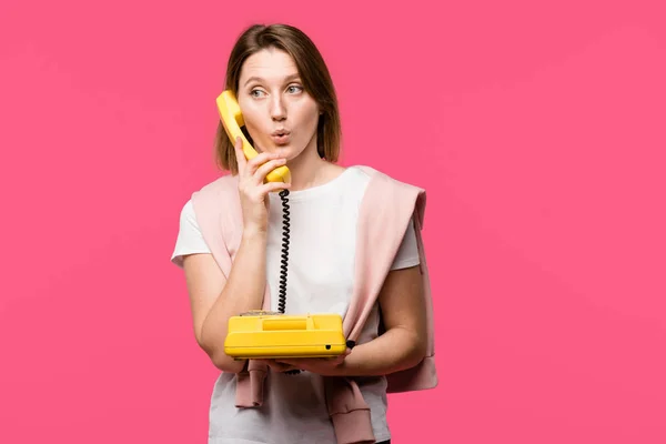 Sorpresa giovane donna che parla per telefono rotante isolato su rosa — Foto stock