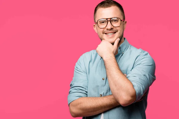 Schöner glücklicher Mann, der mit der Hand am Kinn steht und isoliert auf rosa in die Kamera lächelt — Stockfoto