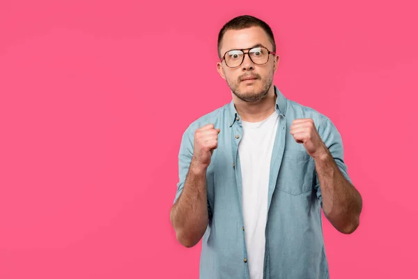Aggressive man with clenched fists looking at camera isolated on pink — Stock Photo
