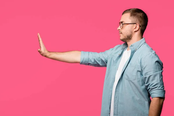 Vista lateral del hombre haciendo un gesto no con la mano y mirando hacia otro lado aislado en rosa - foto de stock