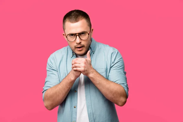 Junger Mann mit Brille reibt sich die Hände und blickt isoliert in die Kamera auf rosa — Stockfoto