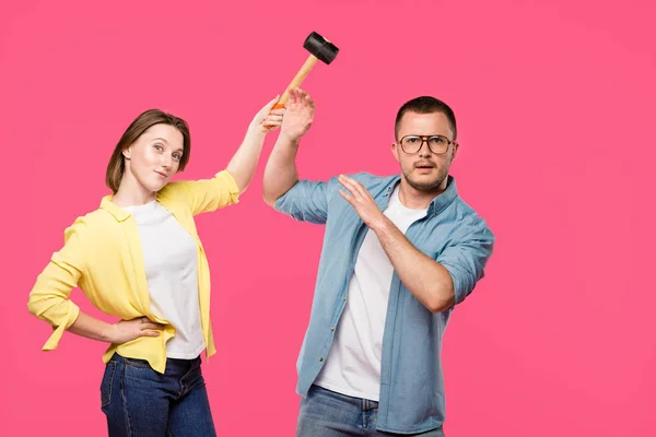 Jeune couple avec marteau regardant caméra isolé sur rose — Photo de stock