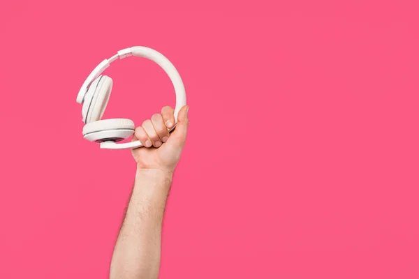 Cropped shot of man holding white headphones isolated on pink — Stock Photo