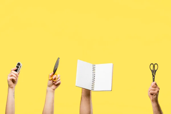 Tiro recortado de mãos masculinas e femininas segurando tesoura, grampeador e bloco de notas em branco isolado em amarelo — Fotografia de Stock