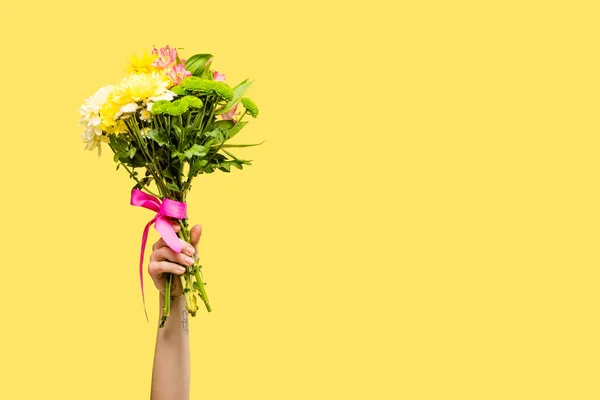 Cropped shot of person holding beautiful bouquet of flowers isolated on yellow — Stock Photo