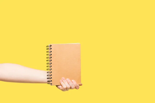 Cropped shot of person holding notebook isolated on yellow — Stock Photo