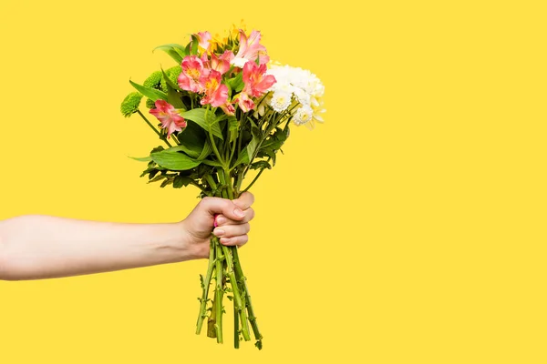 Tiro recortado de la persona que sostiene hermoso ramo de flores aisladas en amarillo - foto de stock