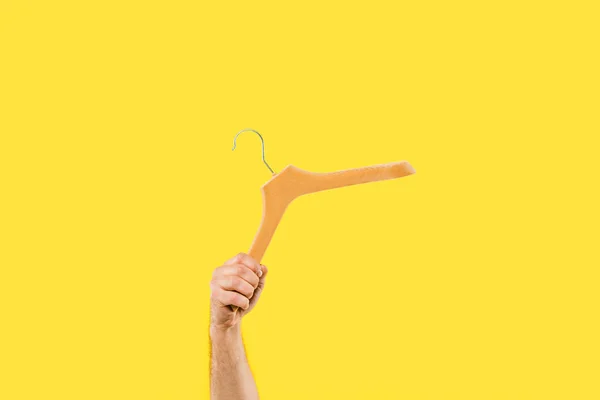 Tiro recortado de la persona que sostiene la percha de madera aislada en amarillo - foto de stock