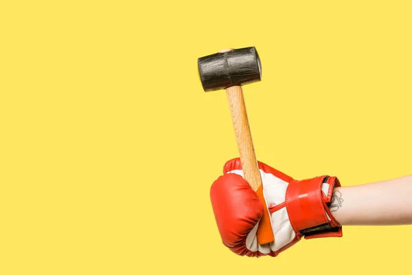 Cropped shot of person in boxing glove holding hammer isolated on yellow — Stock Photo