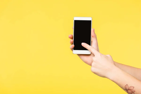 Imagen recortada de la persona que sostiene el teléfono inteligente con pantalla negra aislada en amarillo - foto de stock