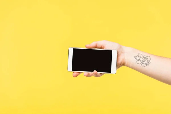 Cropped shot of person holding smartphone with blank screen isolated on yellow — Stock Photo