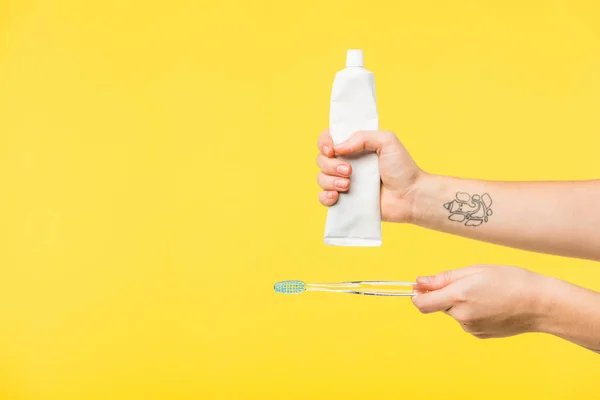 Cropped shot of person holding toothbrush and toothpaste isolated on yellow — Stock Photo