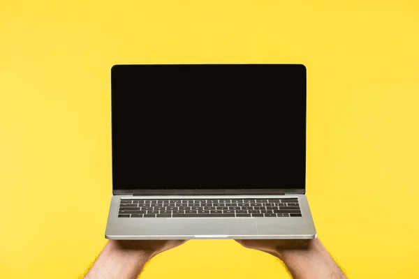 Обрізаний знімок людини, що тримає ноутбук з порожнім екраном ізольовано на жовтому — стокове фото