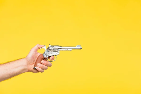 Cropped shot of person holding revolver isolated on yellow — Stock Photo