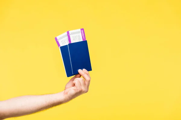 Cropped shot of person holding passports and boarding passes isolated on yellow — Stock Photo