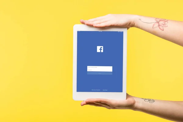 Cropped shot of person holding digital tablet with facebook app isolated on yellow — Stock Photo