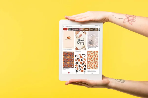 Cropped shot of person holding digital tablet with pinterest app isolated on yellow — Stock Photo