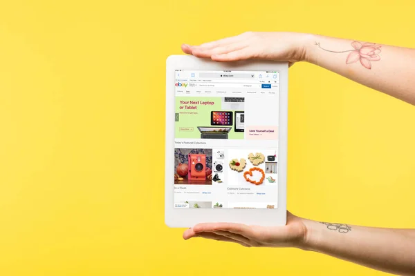 Cropped shot of person holding digital tablet with ebay website on screen isolated on yellow — Stock Photo