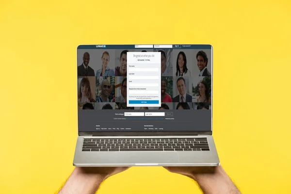 Cropped shot of person holding laptop with linkedin website on screen isolated on yellow — Stock Photo