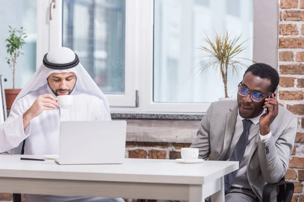 African american businessman talking on smarthphone near arabian partner — Stock Photo