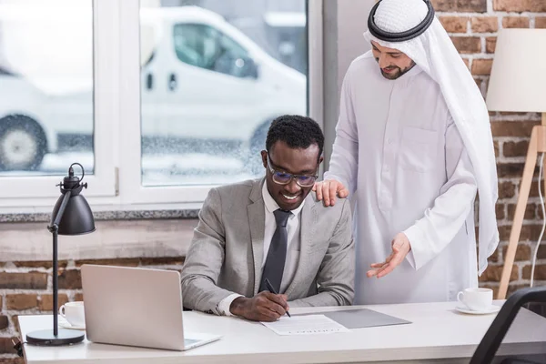 Африканский американский бизнесмен подписывает контракт в современном офисе — стоковое фото