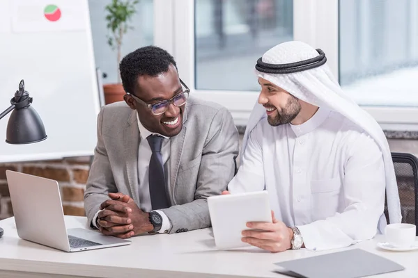 Partenaires commerciaux multiethniques utilisant un appareil numérique dans un bureau moderne — Photo de stock