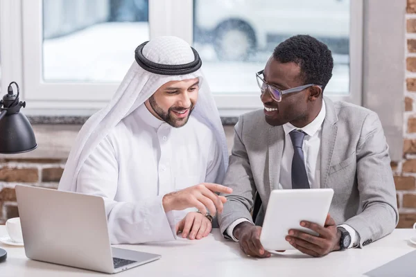 Hombre de negocios árabe apuntando a la tableta digital en la oficina moderna - foto de stock