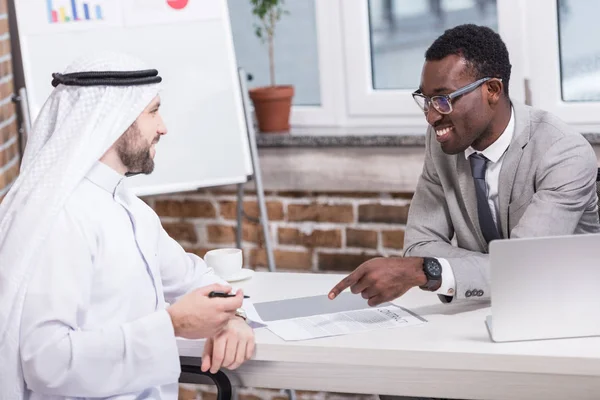African american businessman pointing at contract while arabic partner holding pen — Stock Photo