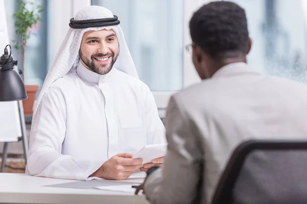 Uomo d'affari arabo sorridente e con tablet digitale in carica — Foto stock