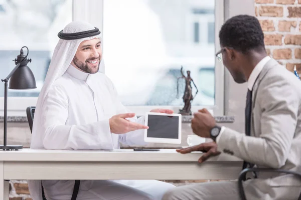 Arabian businessman showing digital tablet and smiling in office — Stock Photo