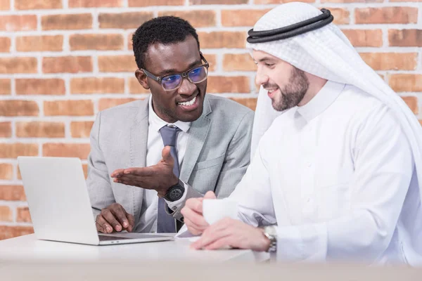 Homme d'affaires afro-américain montrant ordinateur portable dans un bureau moderne — Photo de stock