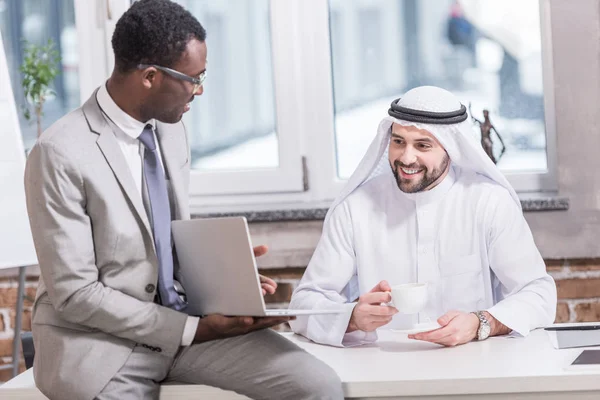 Hombre de negocios árabe mirando el ordenador portátil en la oficina - foto de stock