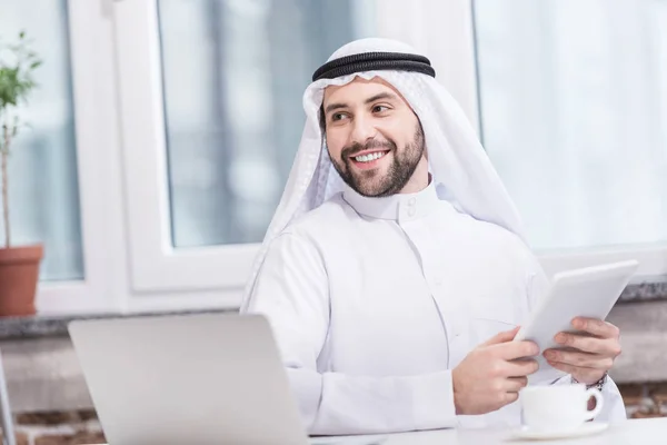 Homem de negócios árabe segurando tablet digital no escritório moderno — Fotografia de Stock