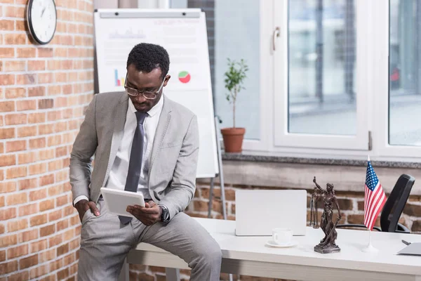 Homme d'affaires afro-américain regardant tablette numérique avec la main dans la poche — Photo de stock