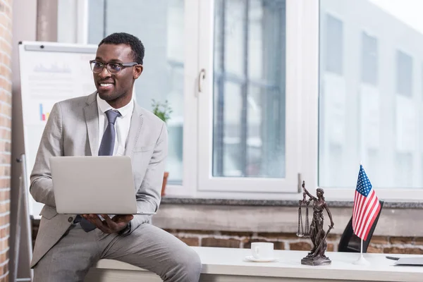 Afrikanisch-amerikanischer Geschäftsmann hält Laptop in modernem Büro — Stockfoto