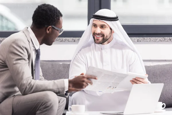 Empresários multiculturais conversando e sorrindo no escritório moderno — Fotografia de Stock