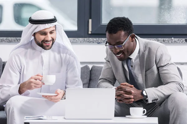 Geschäftsleute schauen auf Laptop und lächeln im modernen Büro — Stockfoto