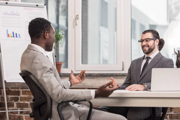 Beaux partenaires d'affaires multiethniques assis au bureau — Photo de stock