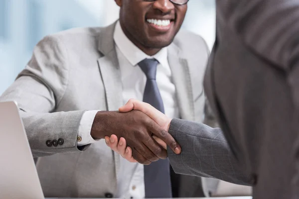 Abgeschnittene Ansicht multiethnischer Geschäftsleute in Anzügen beim Händeschütteln — Stockfoto