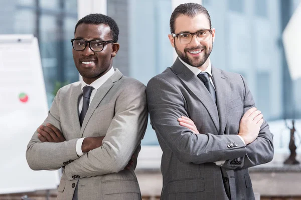 Vue rapprochée de deux hommes d'affaires multiethniques les bras croisés dans le bureau — Photo de stock