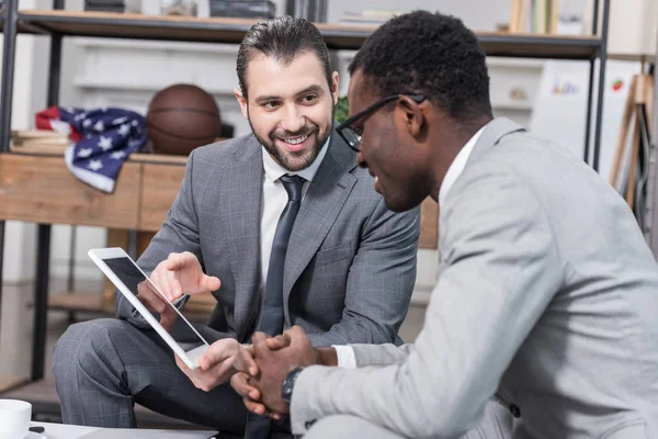 Afrikanischer amerikanischer Geschäftsmann schaut Geschäftspartnern digitales Tablet im Büro an — Stockfoto