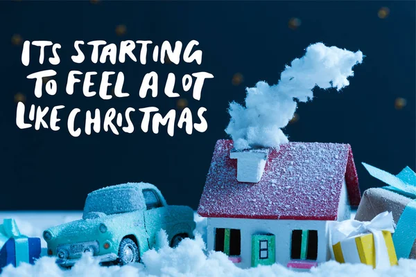 Plan rapproché de la voiture miniature avec des cadeaux de Noël et la maison couverte de neige la nuit, avec 
