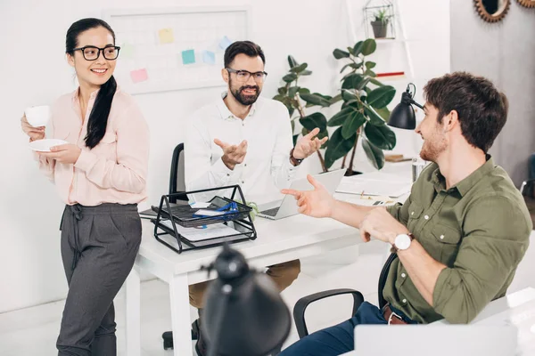 Happy office managers holding coffee cup and talking in office — Stock Photo