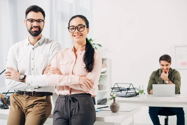 Office managers with arms crossed smiling and looking at camera in office — Stock Photo